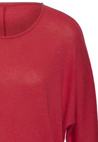 Rotes gestricktes Oberteil mit weitem Ausschnitt, langen Ärmeln und strukturiertem Material. Der Stoff wirkt leicht und atmungsaktiv.