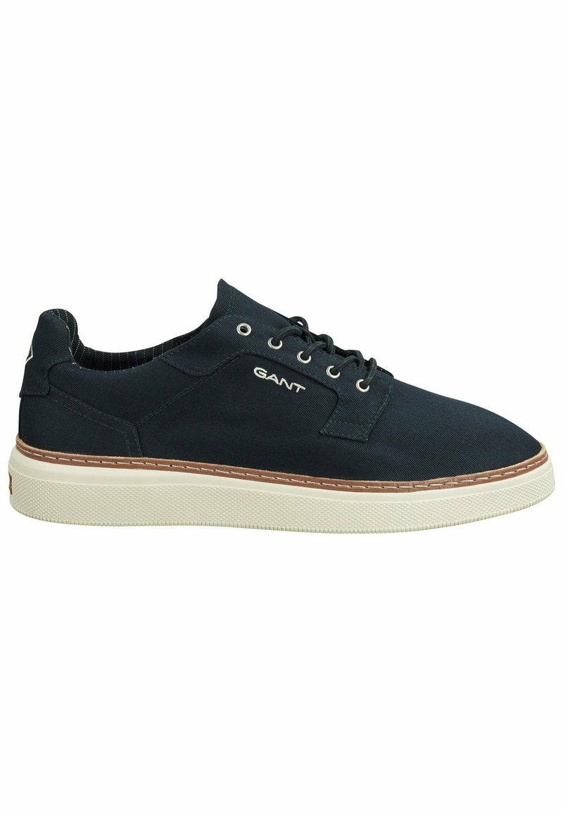Marineblaue Canvas-Sneaker mit weißer Gummisohle, braunem Stich, Schnürverschluss und Markenlogo an der Außenseite. Glatte Textur.