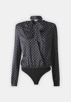Musta bodysuit, jossa on pitkät hihat, rusetin muotoinen kaula-aukko ja valkoisia pilkkuja. Kankaalla on sileä, kiiltävä pinta ja rypytetty yksityiskohta.
