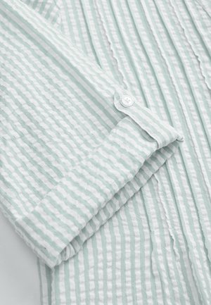 Ljus mintgrön långärmad skjorta med tunna vita vertikala ränder, mjuk textur och detaljerade manschetter med knappar.