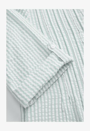 Hellgrünes Hemd mit langen Ärmeln in Minzfarbe, das dünne weiße vertikale Streifen, eine weiche Textur und einen Knopfmanschetten-Detail aufweist.