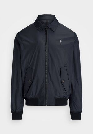 Marineblå bomberjakke lavet af letvægtsmateriale. Har en spids krave, for-lynlås, to skrå lommer og ribbede manchetter.