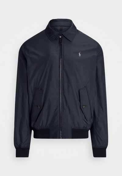 Jakna bomber temno modre barve iz lahkega materiala. Ima koničast ovratnik, sprednji zadrgo, dve kotni žepi in rebrasta manšeta.