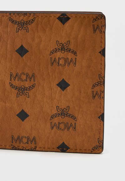 Rudas odinis piniginė su tekstūruota paviršiumi. Visame paviršiuje yra pakartoti juodi MCM logotipai ir deimanto raštas, su kontrastingomis siuvimo detalėmis.