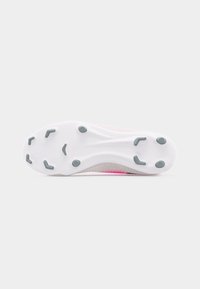 Suela blanca de un zapato de fútbol con seis tachones grises tipo cuchilla y dos tachones circulares sobre un fondo blanco liso.