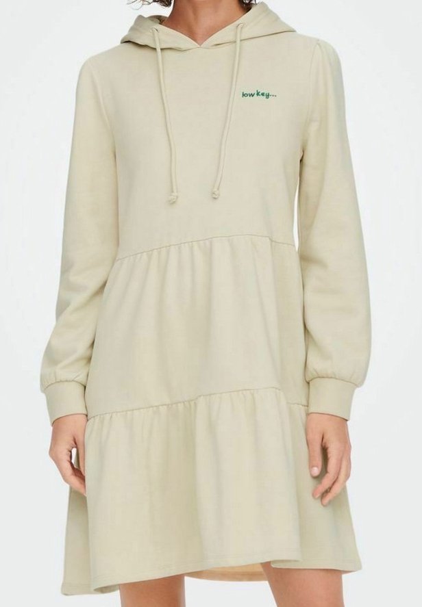 Vestido sudadera beige claro con mangas largas, diseño en capas y texto frontal "low key...". Está hecho de material suave. Presenta una capucha con cordones.