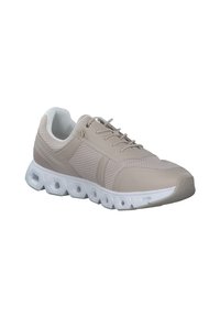 Scarpa sportiva beige con tomaia in mesh, design testurizzato e suola esagonale bianca. Presenta lacci e un collare imbottito per il comfort.