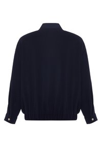 Marinblå, lätt jacka med hög krage, sänkta axlar och elastisk nederkant. Har knäppta ärmar och en slät textur.