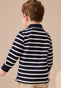 Marineblau-weiß gestreifte Langarm-Poloshirt mit Kragen, ausgestattet mit seitlichen Schlitzen am Saum und gerippten Bündchen. Das Material wirkt weich und strukturiert.