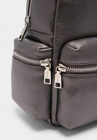 Mørkegrå tekstureret læderrygsæk med to frontlommer med lynlås og sølvhardware detaljer. Glat overflade og solid konstruktion.