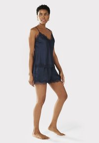 Navy satin lingerie set with lace accents. Features a camisole with adjustable straps and matching shorts with scalloped edges.