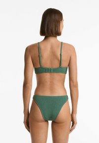 Set di bikini verde con texture, caratterizzato da un top aderente con spalline regolabili e chiusura a ganci, abbinato a slip bikini a vita bassa.