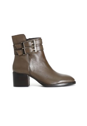 Boot din piele maro până la gleznă, cu vârf rotund, două catarame cu curea și toc pătrat. Textură netedă cu accente metalice pe curele.