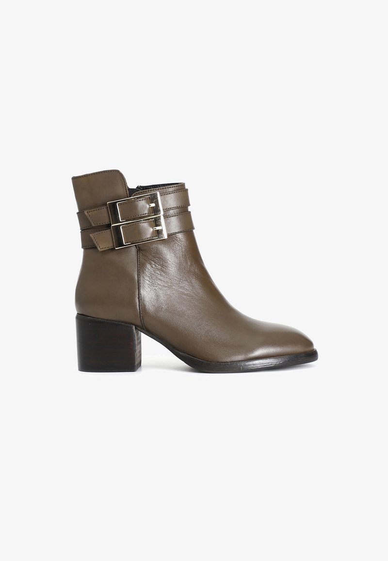 Boot din piele maro până la gleznă, cu vârf rotund, două catarame cu curea și toc pătrat. Textură netedă cu accente metalice pe curele.