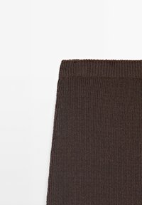 Tissu tricoté côtelé marron foncé avec une large ceinture élastique, présenté à plat sur un fond blanc.