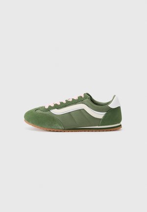 Sneakers verdi con un mix di camoscio testurizzato e tessuto liscio, con dettagli bianchi, lacci rosa e suola in gomma marrone.
