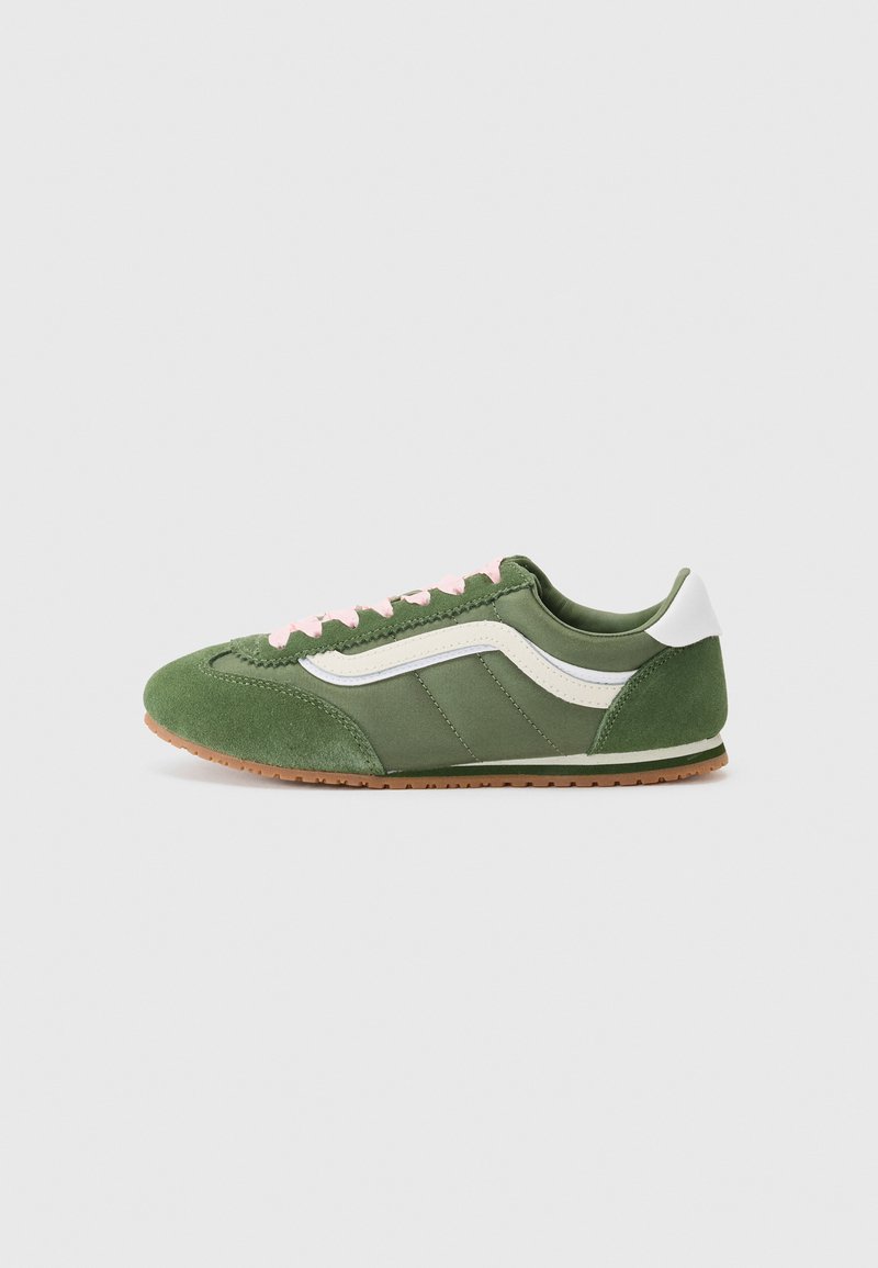 Grønne sneakers med en blanding av teksturert semsket skinn og glatt stoff, med hvite detaljer, rosa snører og en brun gummisåle.