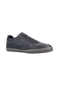 Zapatilla deportiva negra hecha de materiales de cuero y sintéticos. Presenta una superficie suave, detalles perforados y una suela de goma.