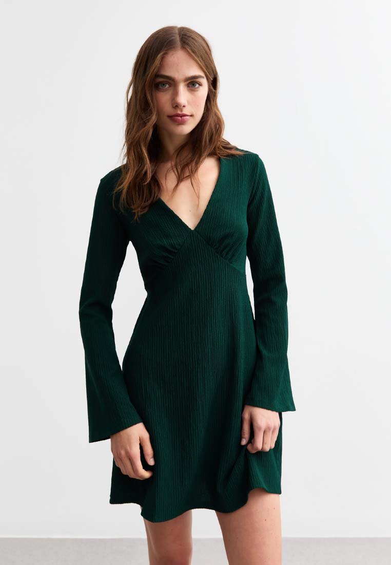 Abito avvolgente verde realizzato in tessuto testurizzato, con maniche a campana lunghe e scollatura a V profonda. La gonna si allarga leggermente all'orlo.
