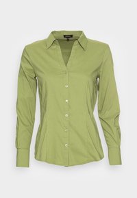 Camicia a maniche lunghe con bottoni in cotone verde chiaro. Presenta un colletto a V e un design aderente. Cinque bottoni frontali e polsini sagomati.