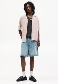 Kortærmet, lyserød ternet skjorte, sort top, denim shorts, sorte sko, grå sokker med lyseblå accenter, sølv kæde accessories.