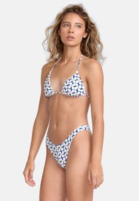 Bikini set má modro-bielo geometrický vzor. Vrchná časť má trojuholníkové košíčky s tenkými ramienkami; dolná časť má vysoký strih.