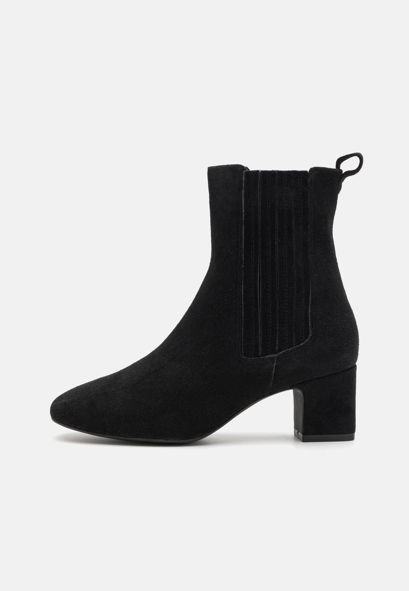 Bottine en daim noir avec talon bloc, panneau latéral élastique et languette arrière sur un fond clair uni.