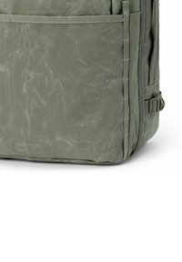 Zaino in tela verde con una finitura texturizzata, dotato di una tasca laterale, cuciture rinforzate e una zip robusta per la chiusura.