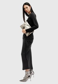 Zwart langemouwen jurk met een gathered taille, gecombineerd met metallic zilveren accentlaarzen en een bijpassende clutch. Soepele textuur, slim fit.