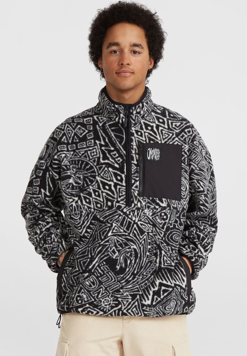 Fliisist pullover musta ja valge geomeetrilise mustriga, poolt tõmblukuga ja ühtlane must rinna tasku. Omab elastseid varrukaotste ja äärte lõpetusi.