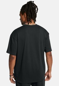 Sort bomulds t-shirt med en afslappet pasform, korte ærmer og rund hals. Har ensartet bagsidedesign og diskrete syninger.