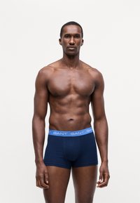 Boxers navy en coton doux, avec une ceinture GANT en bleu clair. Le design est ajusté avec une texture lisse.