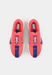 Běžecké boty Nike v jasné korálové barvě s námořnickými akcenty. Síťový svršek, šněrovací design a polstrovaná podrážka pro podporu.