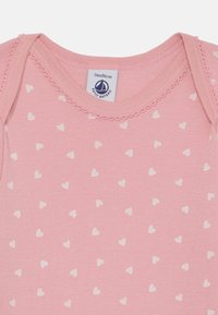 Rožinė medvilninė kūdikio džemperiukas su baltu širdelių raštu, turi nupjautą iškirptę ir etiketę su užrašu "Petit Bateau", dydis 24m/86cm.