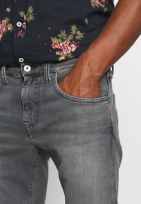 Vaqueros de mezclilla gris con un ajuste slim, que cuentan con cinco bolsillos, costuras clásicas y un sutil acabado desgastado.