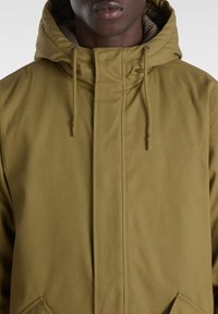 Khaki hooded jacket made from smooth, sturdy fabric. Features a front zip, adjustable drawstrings, and side pockets.