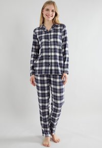 Geruite flanellen pyjam set in navy en wit, bestaande uit een knoopsluiting bovenstuk met een kraag en lange mouwen, en bijpassende rechte pijpen.