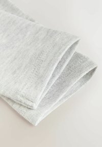 Tissu côtelé gris clair plié avec des coutures visibles, montrant le détail de l'ourlet sur un matériau textile doux.