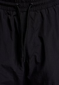 Schwarze Shorts aus leichtem Stoff, mit einem elastischen Bund und einer schwarzen Kordel sowie einer dezenten Textur.