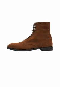 Bota de tobillo de ante marrón con punta redondeada y un bajo tacón negro. Presenta un diseño de cordones con seis ojales y una textura suave.