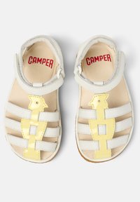 Bílé kožené sandály s akcentem žlutého ptáčka, s popruhovým designem a uzavíráním na suchý zip. Měkký interiér s brandingem "CAMFER".