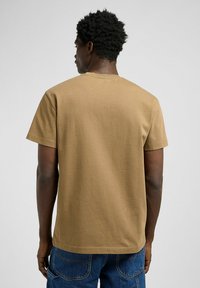 Braunes Baumwoll-T-Shirt mit kurzen Ärmeln, Rundhalsausschnitt und glatter Textur, von hinten betrachtet. Lässiges Design mit minimalen Details.
