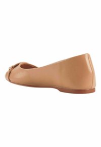 Naakte leren balletschoenen met een ronde neus en een klein strikje. De schoen heeft een platte hak en een gladde textuur.