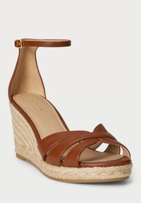 Rudos odinės platformos sandalai su kulkšnies juostele, turintys kryžmines juosteles ir jūrinės virvės apvyniotą kulną, lygus paviršius ir atvira pirštų dizainas.