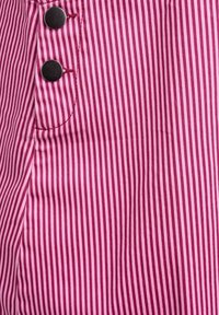 Tela a rayas roja y rosa con líneas verticales, acentos de botones y costuras visibles; textura suave con ligero brillo.