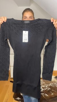 Schwarzes, geripptes Strickkleid mit langen, strukturierten Ärmeln, die mit einem Rautenmuster versehen sind. Enthält ein Etikett, das am Ausschnitt befestigt ist.