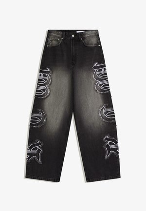 Črne široke jeans hlače z bledim sredinskim delom in šestimi belimi našitki v grafitnem slogu na sprednjih nogah, z dizajnom s petimi žepi.
