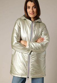 Doudoune métallique argentée avec capuche, fermeture à zip à l'avant et poignets élastiques. Présente une texture lisse et une coupe décontractée.