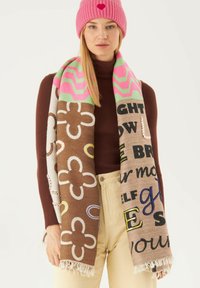 Gewatteerde brei-sjaal in bruin en beige met bloemmotieven, vetgedrukte tekst in meerdere kleuren en een roze chevronrand, met franjes aan de uiteinden.