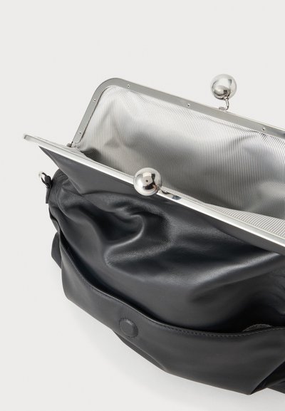 Petit sac en cuir noir avec des plis souples et un fermoir à cadre métallique argenté s'ouvrant sur une doublure intérieure en tissu rayé.